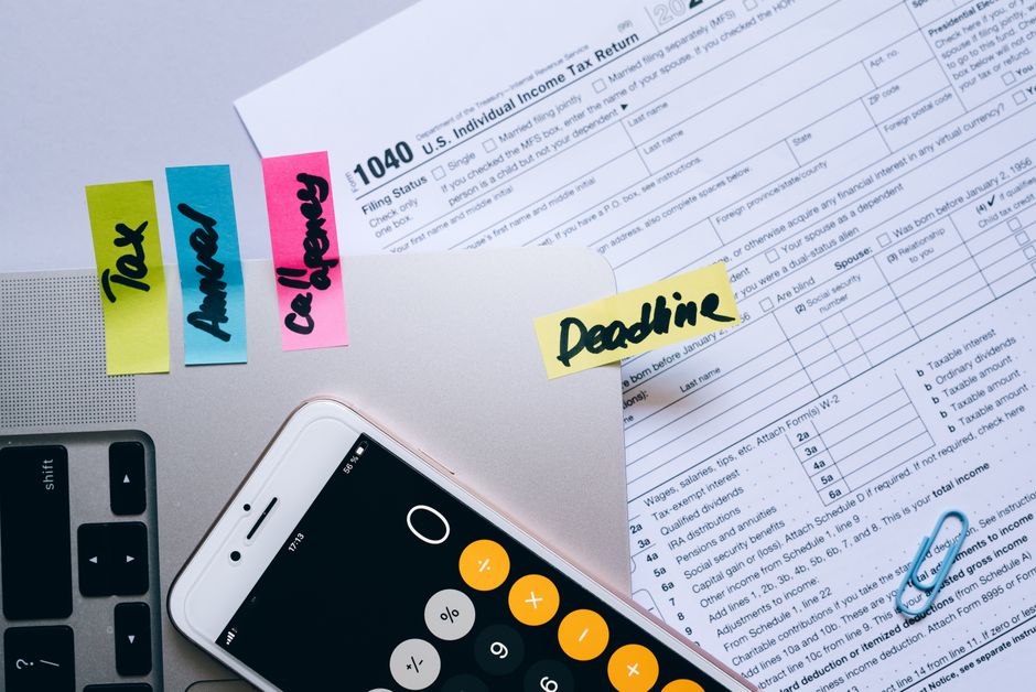 Office desk flat lay showing tax documents, calculator app on smartphone, sticky notes, and paperclips. - Photo by Leeloo The First on Pexels