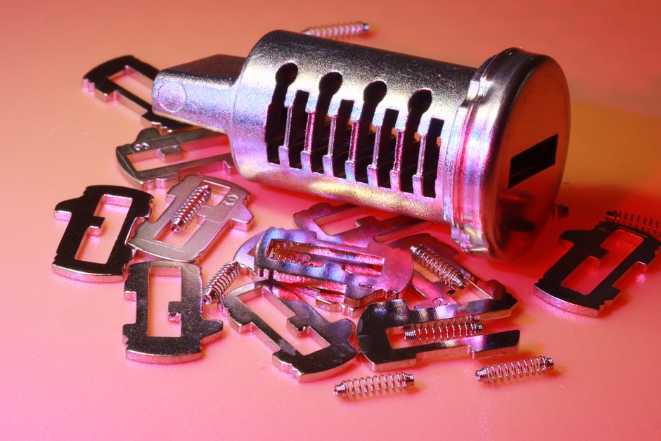 Detailed image of a disassembled lock cylinder and its metal components on a colored surface. - Photo by Nic Wood on Pexels