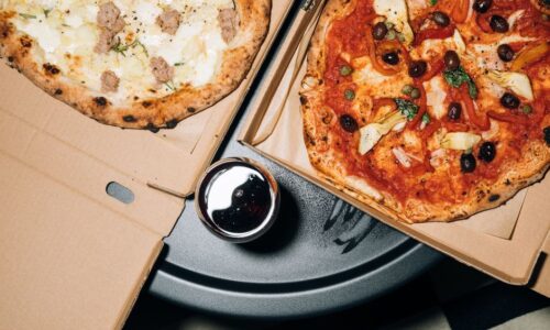 Top view of delicious pizzas in boxes with a refreshing drink, perfect for a cozy meal. - Photo by KoolShooters on Pexels