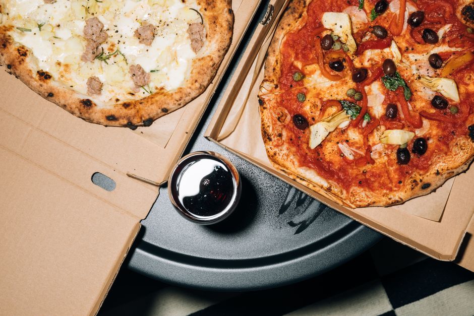 Top view of delicious pizzas in boxes with a refreshing drink, perfect for a cozy meal. - Photo by KoolShooters on Pexels