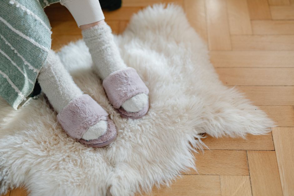 Warm and cozy feet in plush slippers resting on a soft fur rug for relaxation. - Photo by https://kaboompics.com/ on Pexels