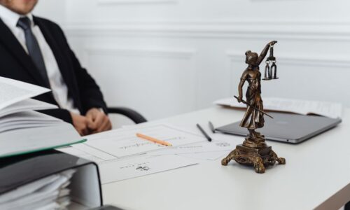 A legal professional's workspace featuring Lady Justice statue, documents, and a laptop. - Photo by https://kaboompics.com/ on Pexels
