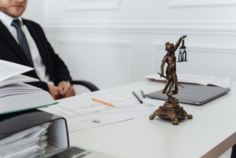 A legal professional's workspace featuring Lady Justice statue, documents, and a laptop. - Photo by https://kaboompics.com/ on Pexels